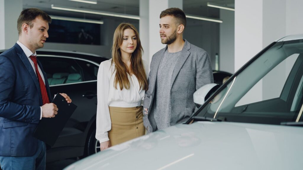 Couple discussing options with a car salesman inside a dealership.